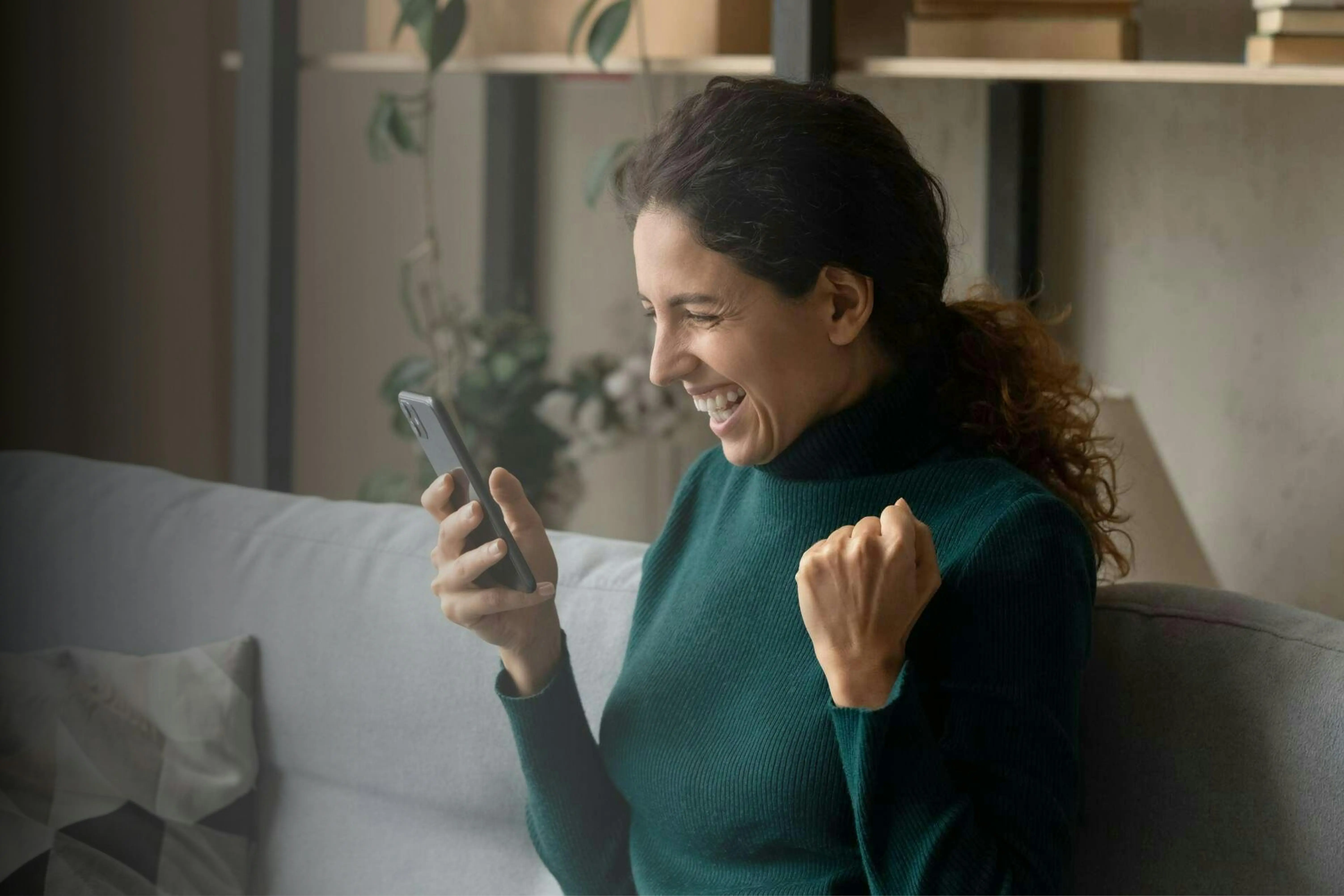 Mulher segurando celular e sorrindo ao se beneficiar das ofertas do Agibank